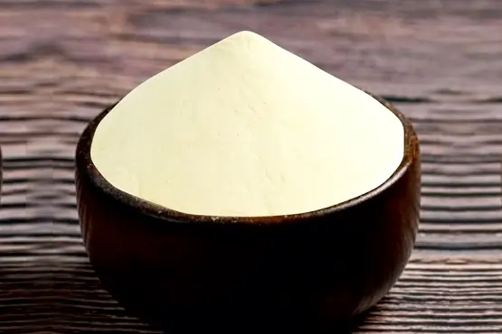A bowl of white potato granules on a wooden table