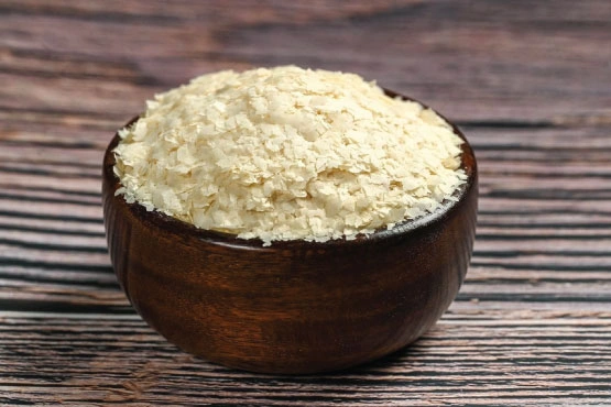A bowl of white potato flakes on a wooden table